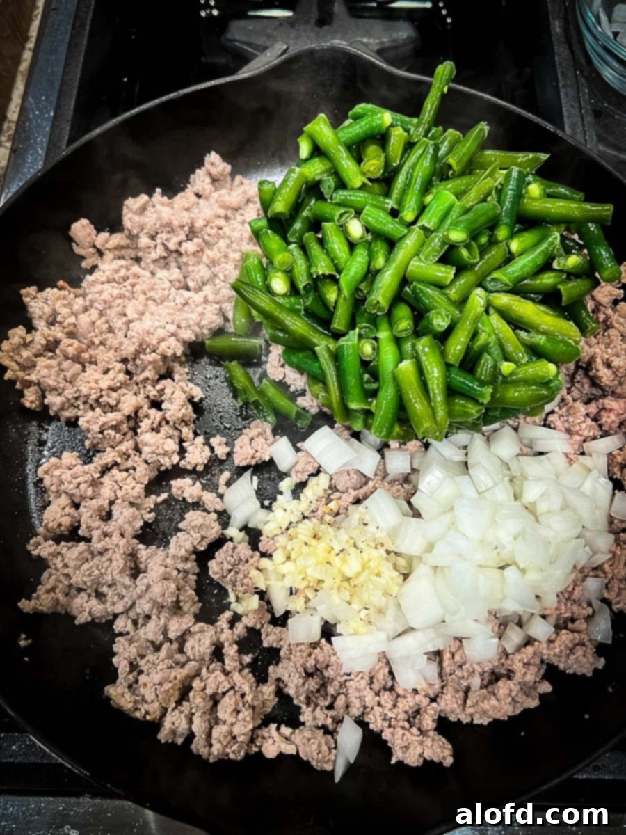 Savory Turkey Tater Bake 6 green beans, onions, and garlic are added to the browned ground turkey in a cast iron skillet.