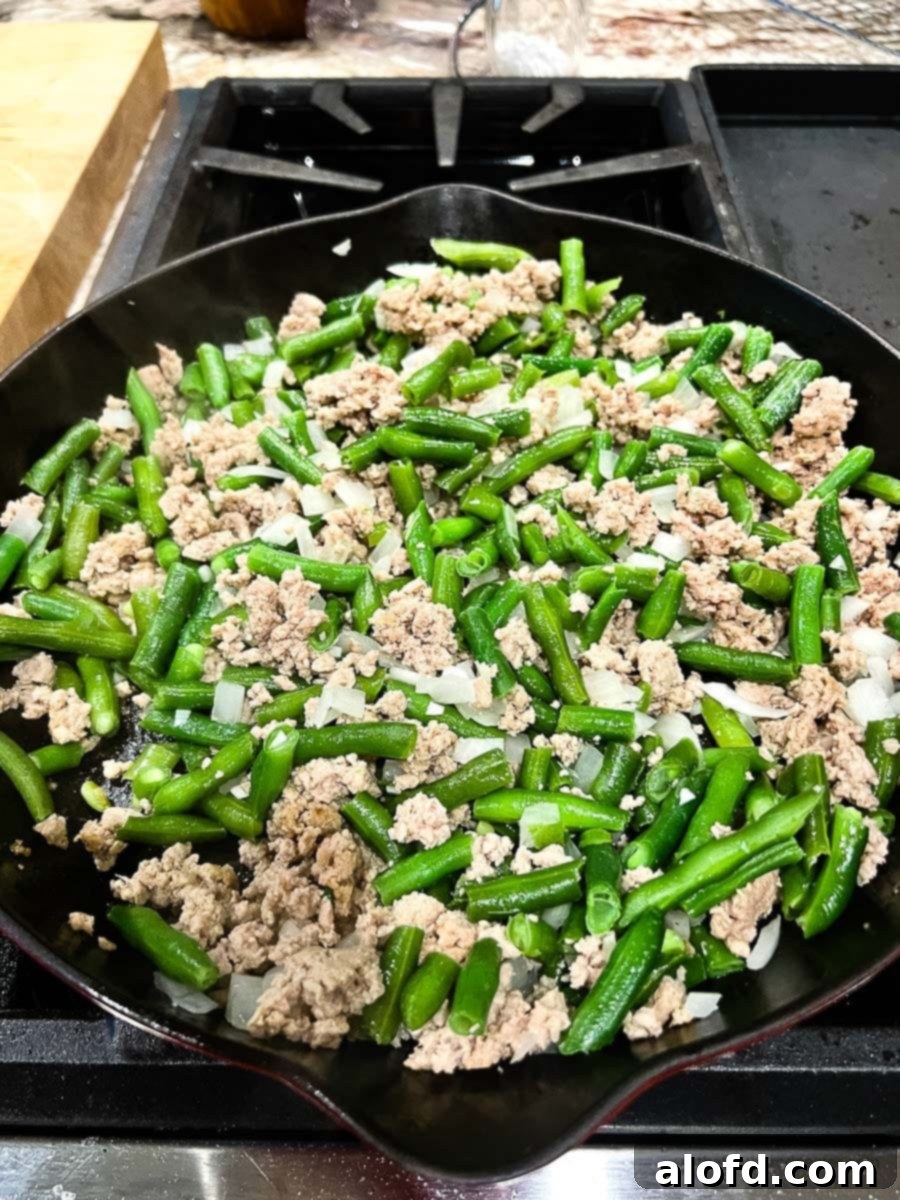 Savory Turkey Tater Bake 7 green beans, onions, garlic, and ground beef all mixed in together in a cast iron skillet.