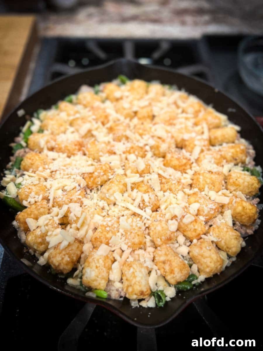Savory Turkey Tater Bake 8 tater tots and cheese layered on top of the ground beef mixture in a cast iron skillet.