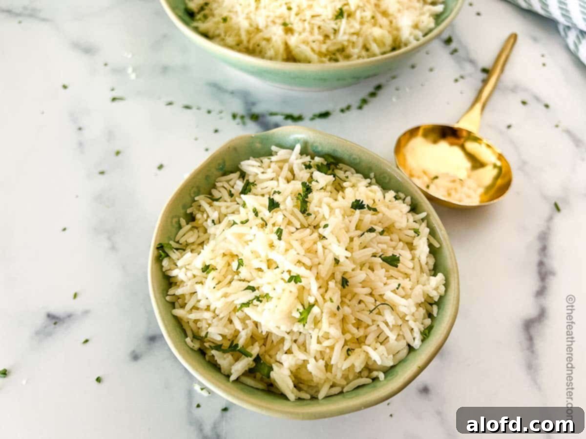 A close-up shot of a green bowl filled with Instant Pot Jasmine rice and a golden serving spoon, with another large bowl of rice slightly out of focus in the background, showcasing the fluffy texture.
