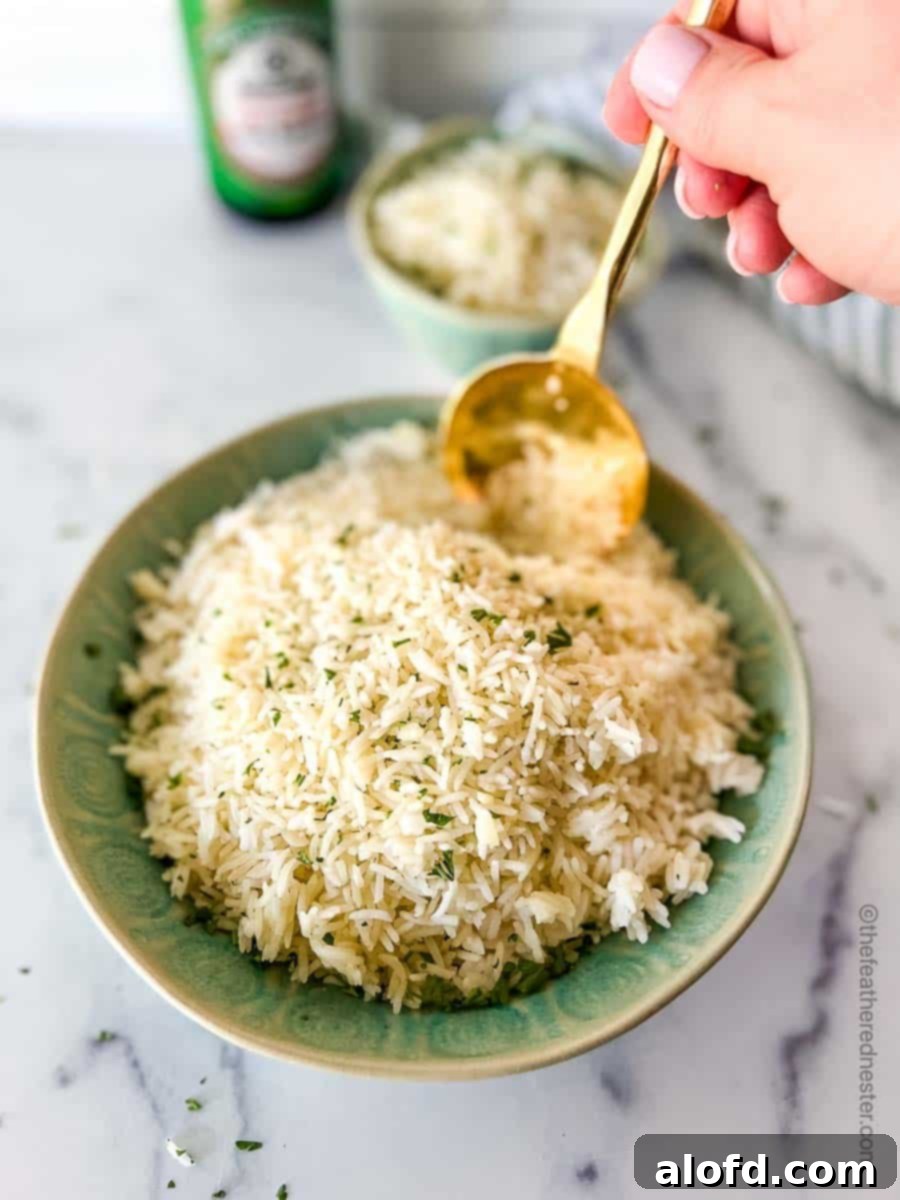 A large green bowl of Instant Pot Jasmine rice with a hand holding a golden serving spoon, ready to serve. In the background, a small bowl of rice, a striped cloth, and a bottle of soy sauce create a warm, inviting scene.