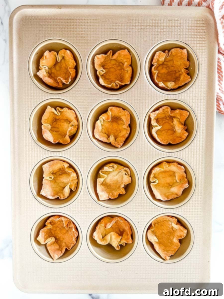 Crispy Baked Wonton Delights 7 Baked wonton cups cooling in a muffin pan, showcasing their perfect shape and golden crispness.