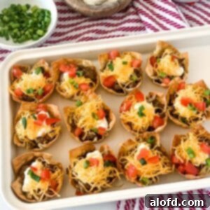 Crispy Taco Wonton Bites 11 A white tray of taco wonton cups on top of a red and white napkin with a bowl of cilantro in the corner, highlighting their appeal as a delicious appetizer.