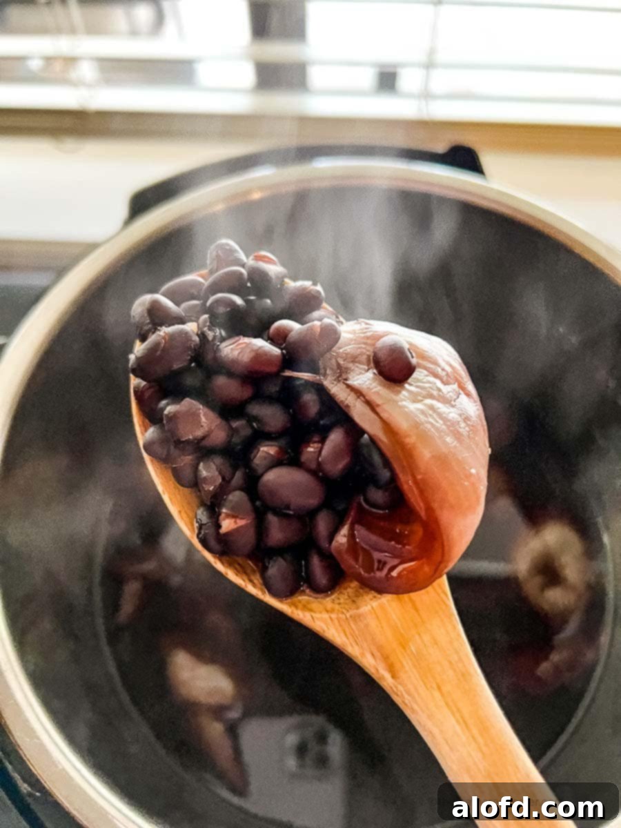 Easy Instant Pot Black Beans 8 A scoop of cooked black beans using a wooden spoon in an Instant Pot.