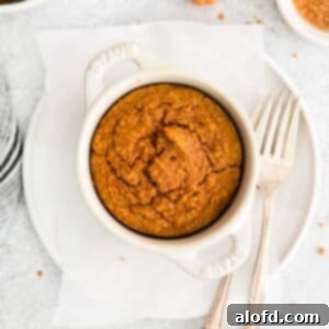 A charming ramekin filled with pumpkin baked oats, with a fork resting alongside, all presented on a simple white plate. This image captures the rustic elegance of a cozy fall breakfast.