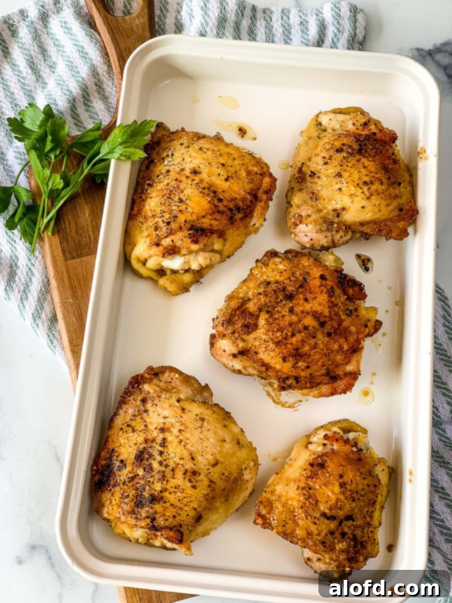 Golden-Crisp Cast Iron Chicken Thighs 3 A white serving tray holding a cast iron skillet filled with beautifully cooked chicken thighs, garnished with fresh herbs.