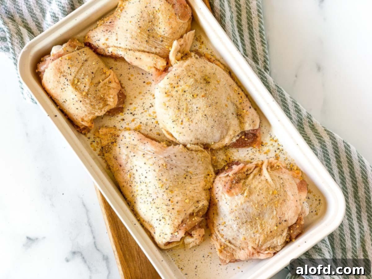 Golden-Crisp Cast Iron Chicken Thighs 5 Raw seasoned chicken thighs arranged on a white tray, ready for pan searing.