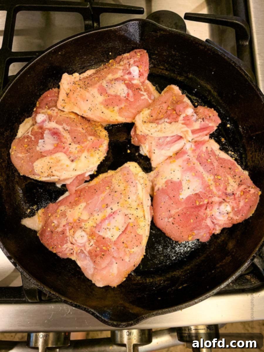 Golden-Crisp Cast Iron Chicken Thighs 6 Chicken thighs searing in a cast iron skillet on the stovetop, showcasing the browning process.