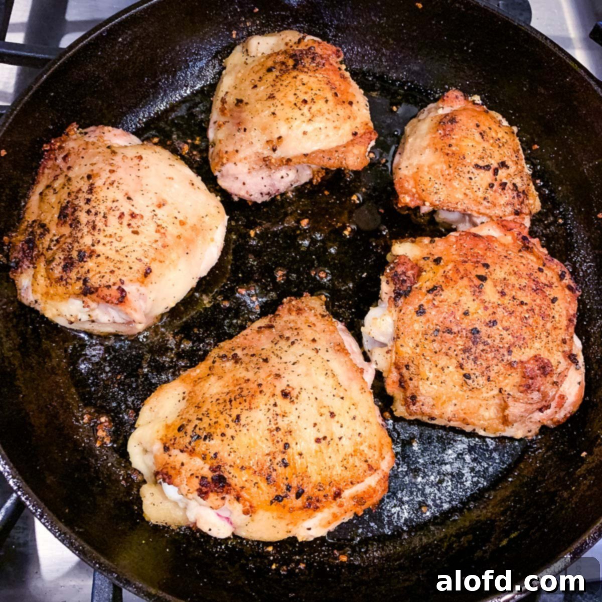 Golden-Crisp Cast Iron Chicken Thighs 7 A cast iron skillet on the stovetop, showcasing chicken thighs being pan-seared to a beautiful golden brown.