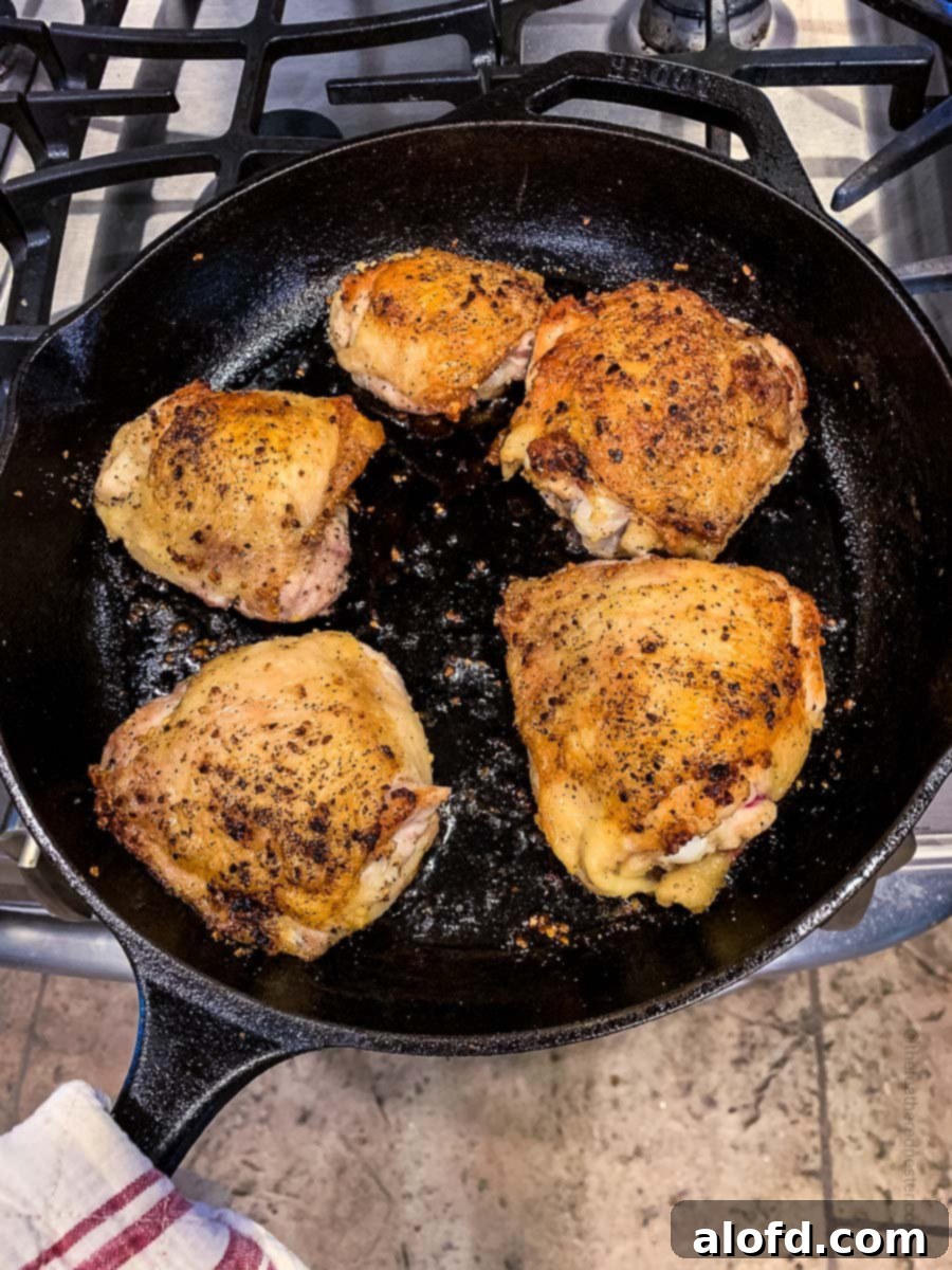 Golden-Crisp Cast Iron Chicken Thighs 8 Perfectly golden brown chicken thighs resting in a cast iron skillet, ready to be served.
