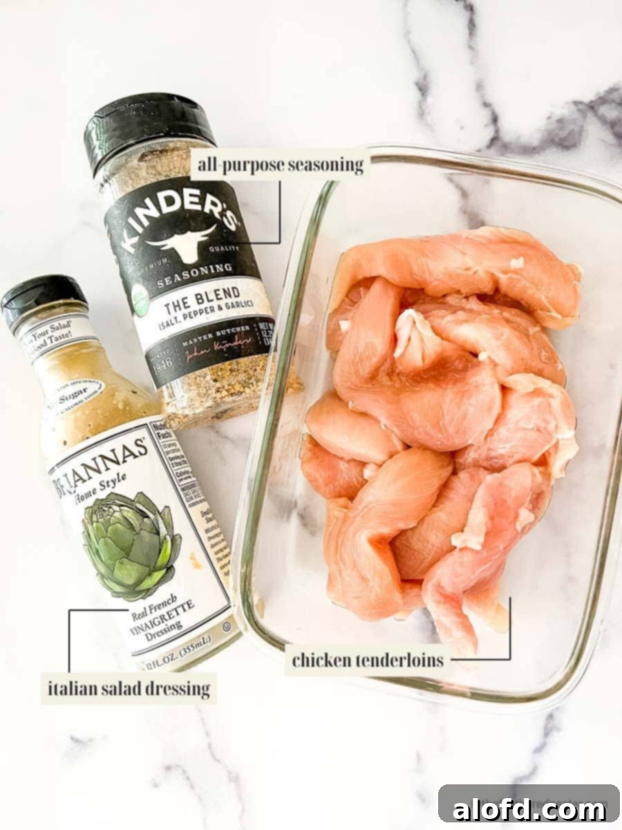 A simple yet appetizing arrangement of ingredients for Oven Baked Marinated Chicken Tenders, featuring raw chicken tenders, a bottle of Italian seasoning, and a vibrant vinaigrette dressing, ready for preparation.