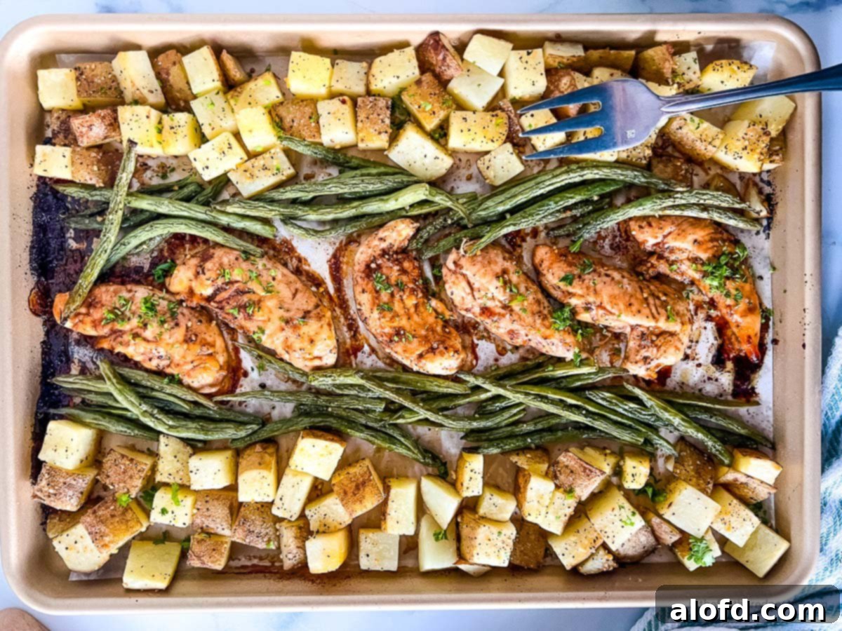 A baking sheet filled with golden-brown oven baked marinated chicken tenders, accompanied by roasted asparagus and potatoes, perfectly cooked and ready to serve.