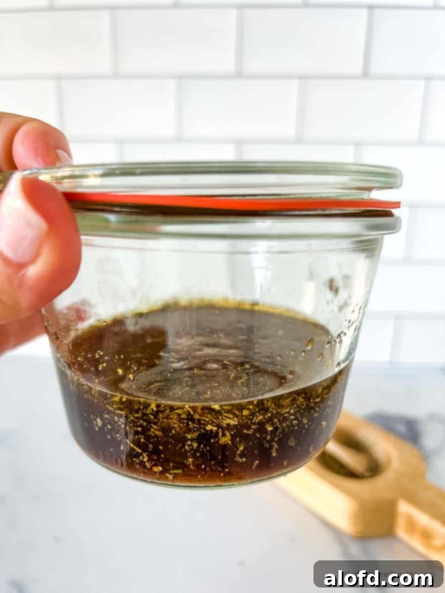 Sweet and Tangy Balsamic Chicken Marinade 7 Balsamic marinade for chicken placed in a glass jar with a salt and pepper cellar in the background.