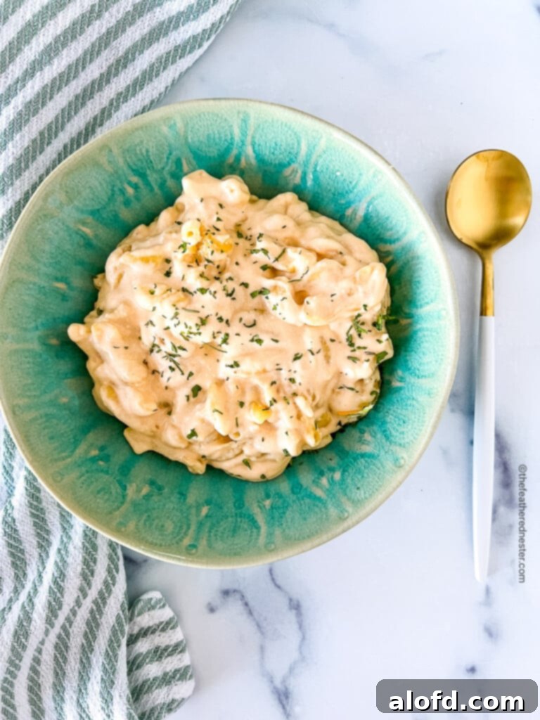 National Pasta Day: Your Ultimate Pasta Feast 2 Creamy slow cooker mac and cheese in a green bowl, with a spoon beside it, ready to be enjoyed.