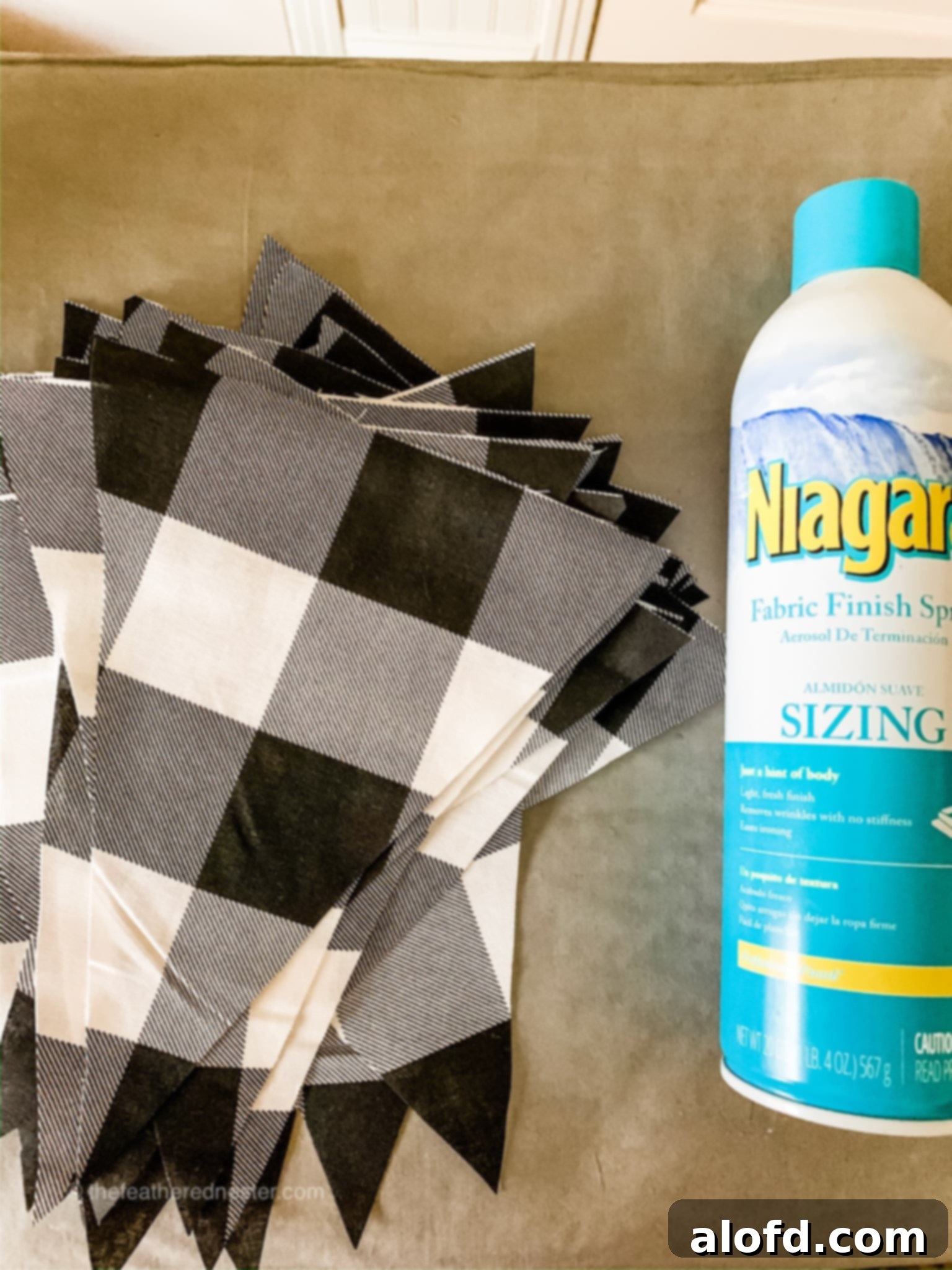 Buffalo plaid pennant with a bottle of fabric finish spray, showing preparation steps.