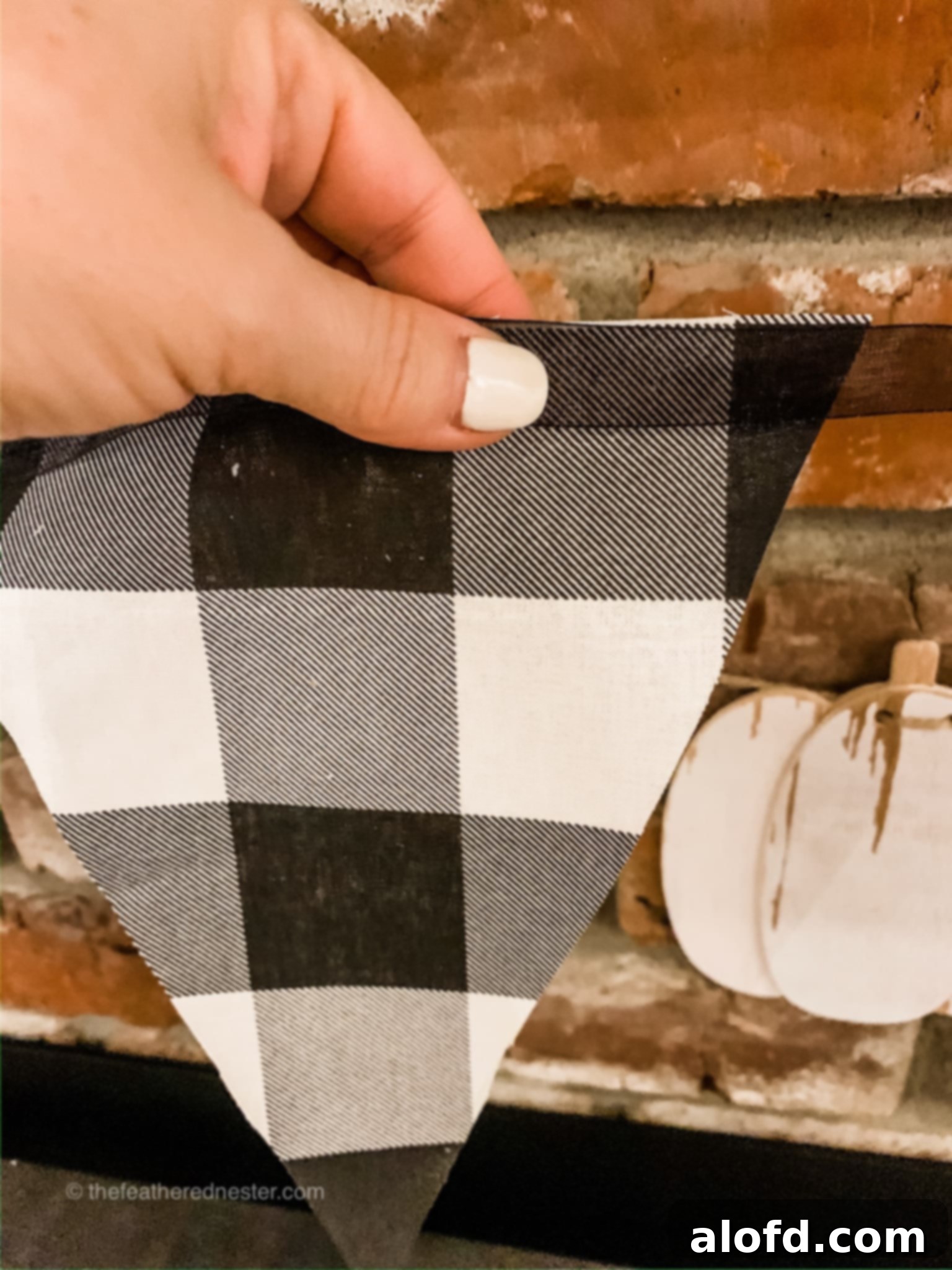 Buffalo plaid pennant garland, showing pinned fabric pieces on ribbon.