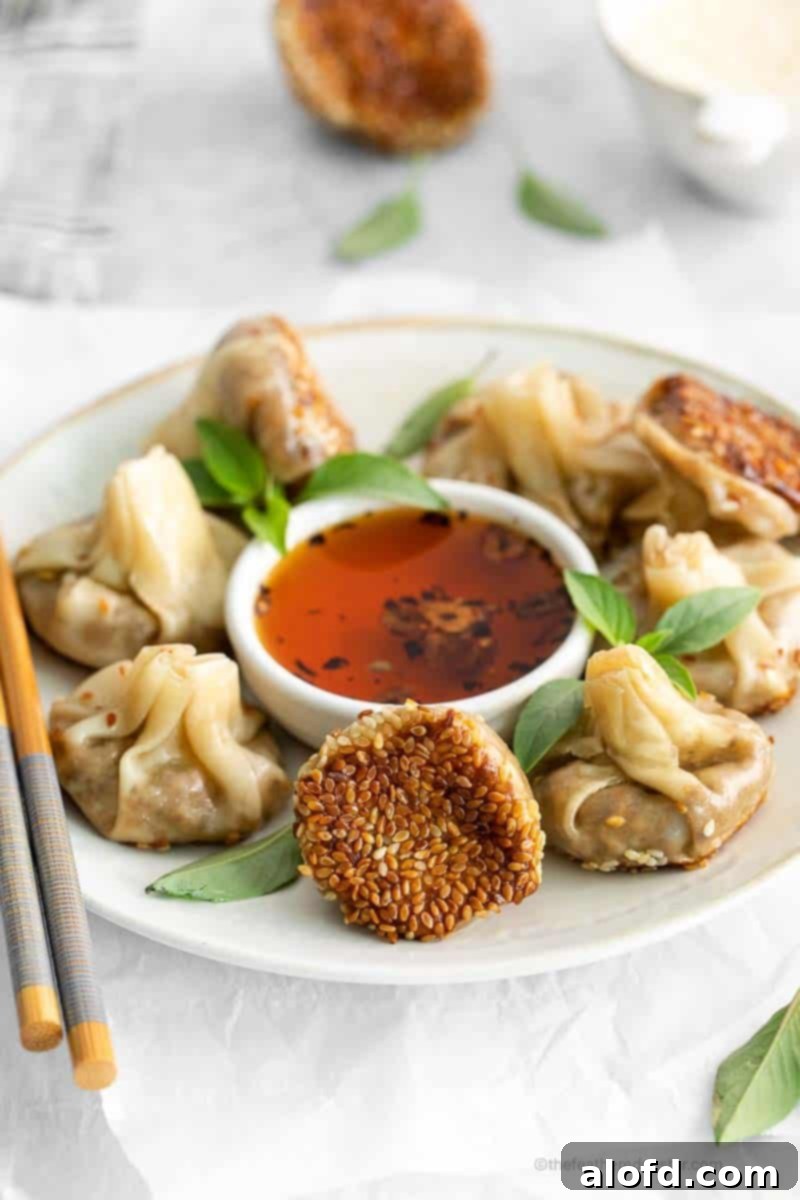 Umami Mushroom Pockets 2 Vegetarian mushroom dumplings artfully arranged on a white plate, accompanied by a small bowl of vibrant garlic chili oil and a pair of elegant chopsticks.