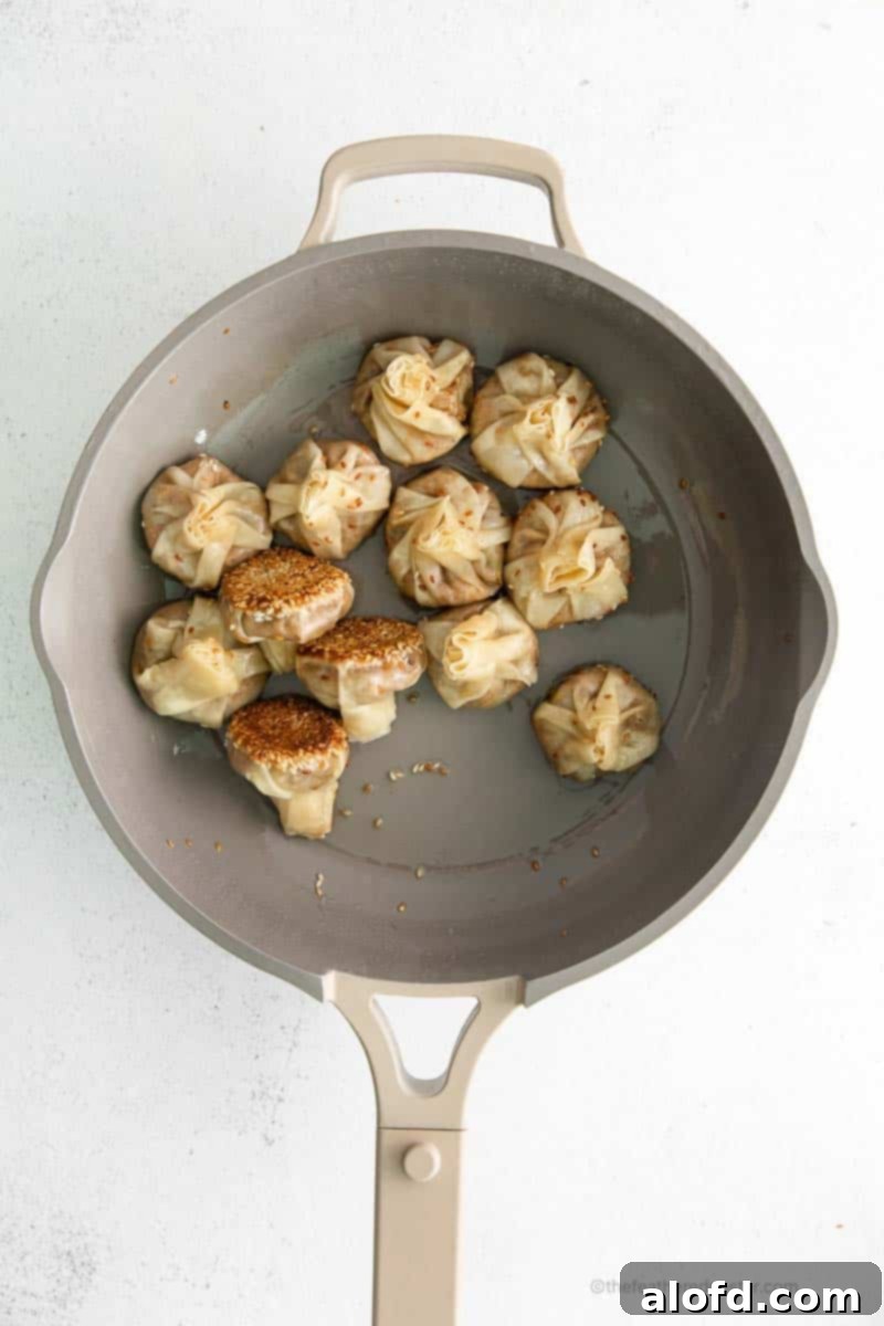 Umami Mushroom Pockets 12 A close-up shot of perfectly cooked mushroom vegetarian dumplings resting in a skillet, showcasing their appealing golden-brown bottoms and tender appearance.