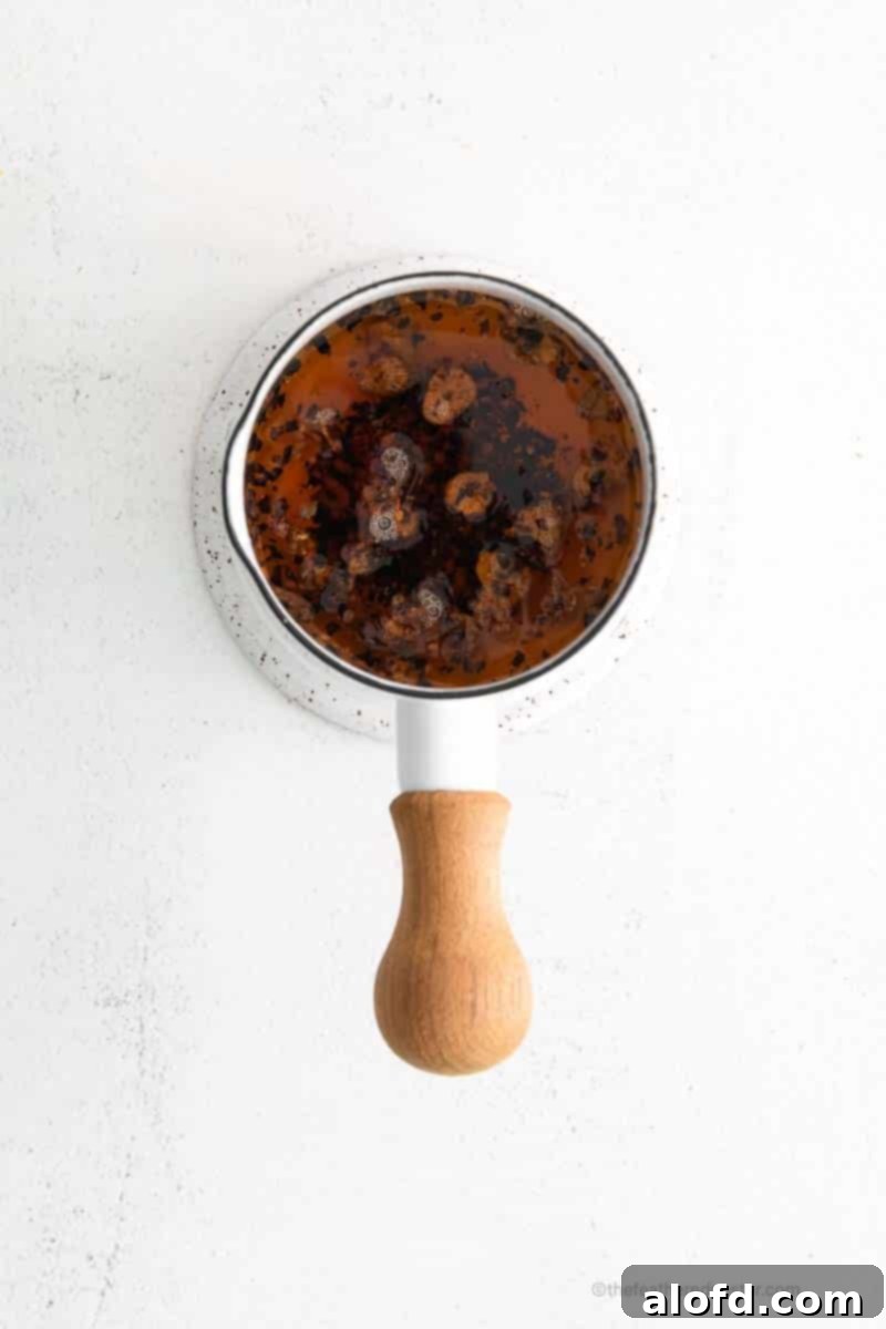 Umami Mushroom Pockets 6 A top-down view of a small saucepan filled with golden garlic chili oil, indicating a freshly prepared, aromatic dipping sauce.