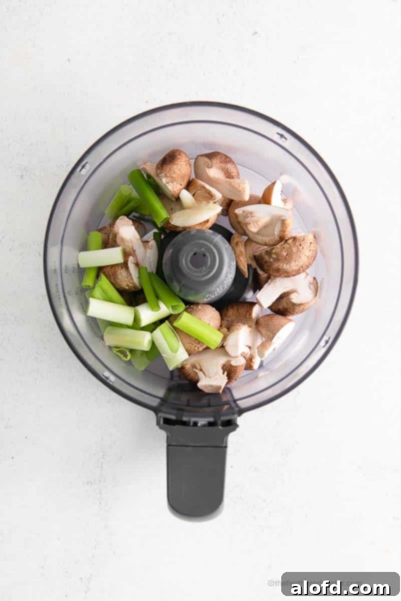 Umami Mushroom Pockets 7 Fresh shiitake mushrooms, garlic cloves, and vibrant green onions are shown inside a food processor bowl, ready to be blended into the dumpling filling.