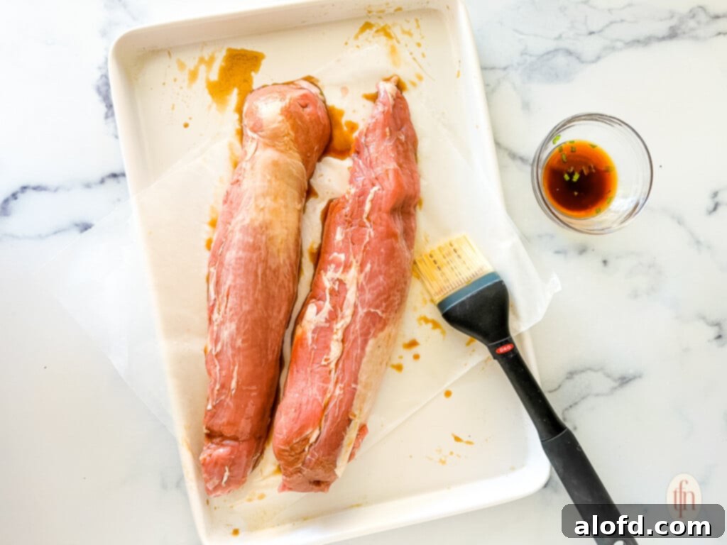 Effortless Sheet Pan Pork Tenderloin 4 Brushing marinade on tenderloins for an Asian pork recipe.