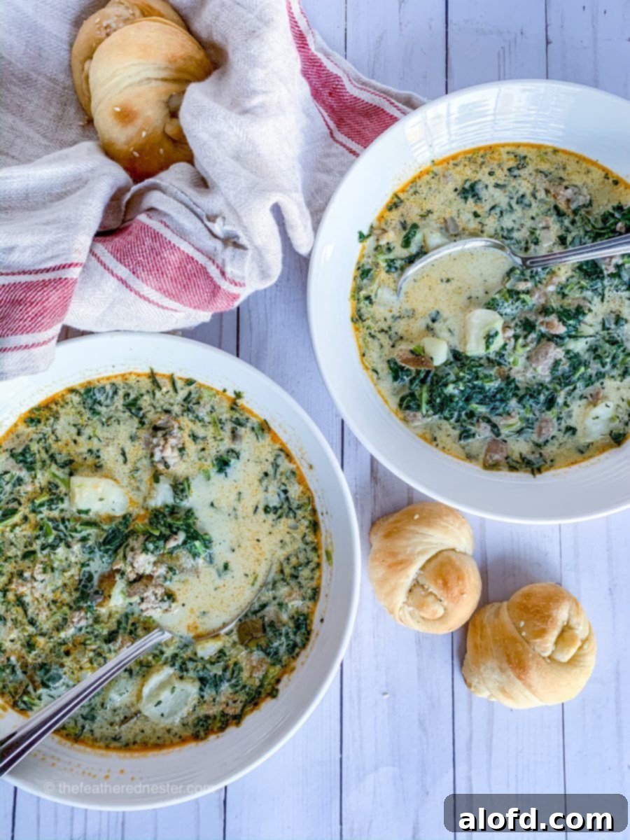 Rustic Tuscan Sausage and Kale Soup 6 Two white bowls of steaming Olive Garden Zuppa Toscana soup copycat recipe, garnished with bacon and fresh herbs.