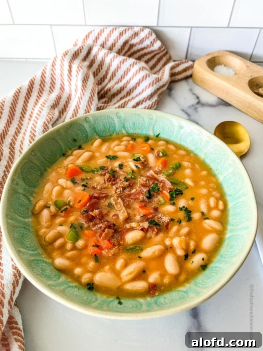 Beyond the Can: 3 Smart Ways to Cook Dried Beans 10 A green bowl with great northern bean soup and red kitchen towel, salt and pepper cellar, and golden spoon at the back.