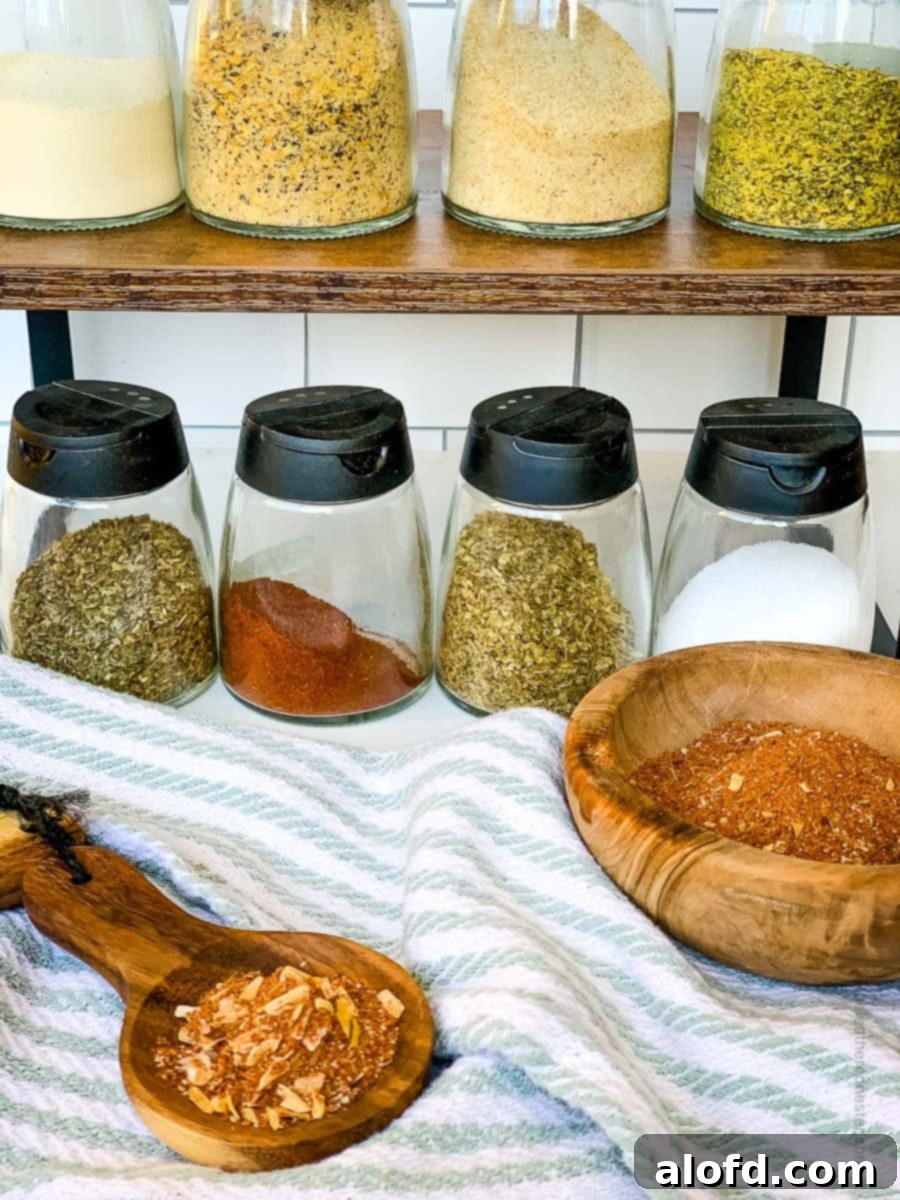 Ultimate Chicken Taco Mix 5 Ingredients for making chicken taco seasoning placed in individual containers and a wooden spoon and bowl with created seasoning in it.