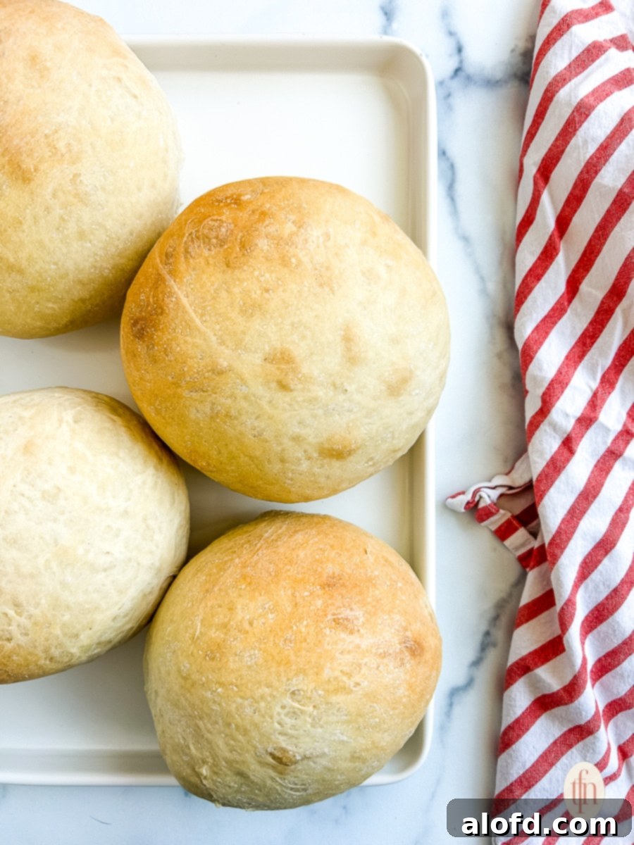 Artisan Sourdough Soup Bowls 10 Two perfectly baked, golden-brown sourdough bread bowls resting on a baking sheet, having just come out of the oven. Their rounded tops and crusty exteriors are clearly visible.