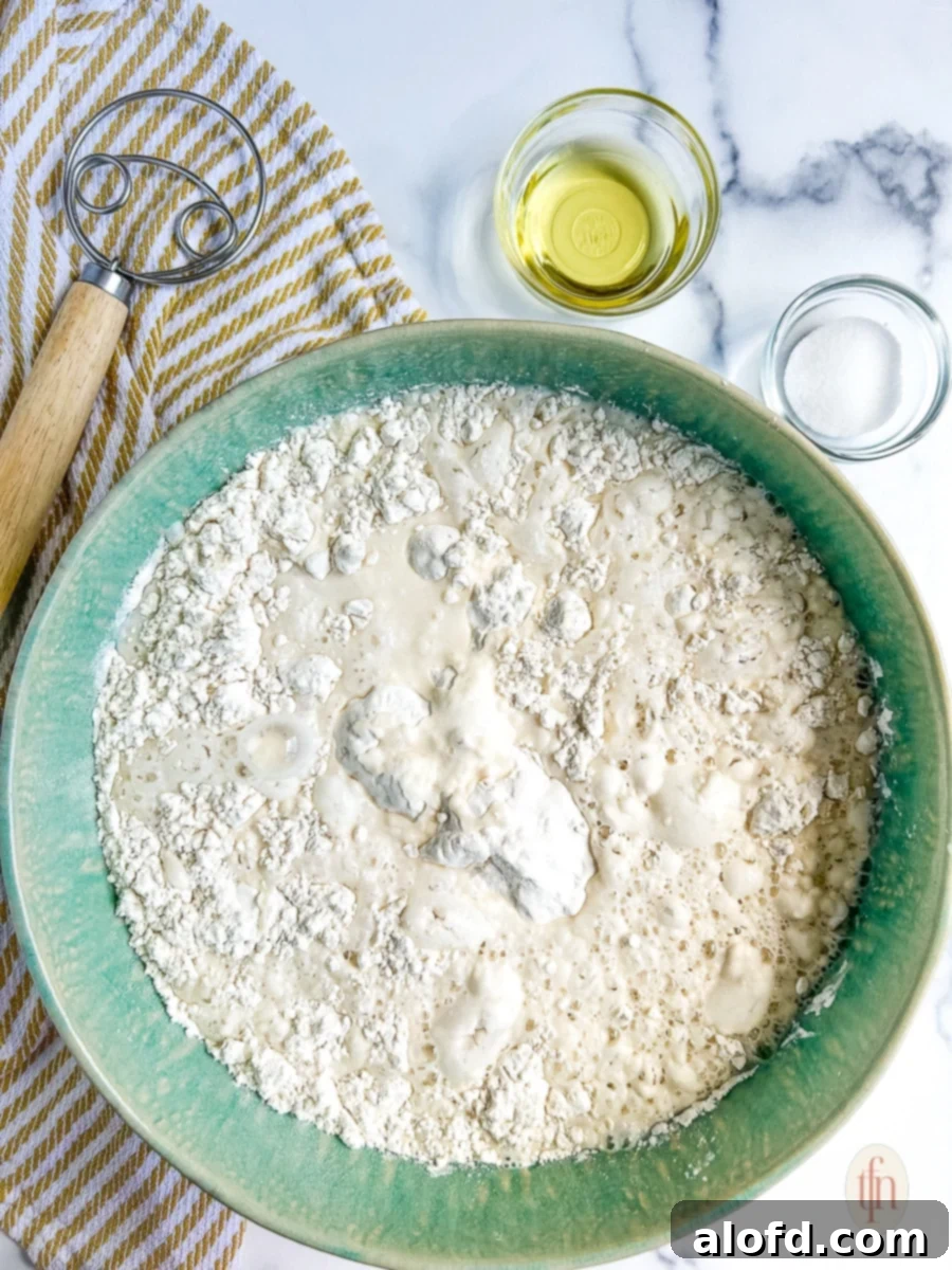 Artisan Sourdough Soup Bowls 6 A large ceramic bowl filled with the initial mixture of sourdough bread dough, showing a shaggy, uneven texture with dry flour still visible, ready for further mixing.