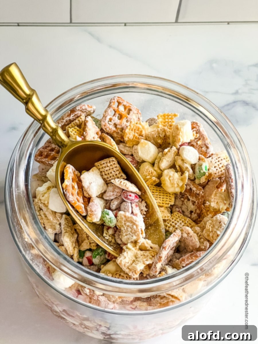 A jar of Christmas crack Chex mix with scoop in the jar.