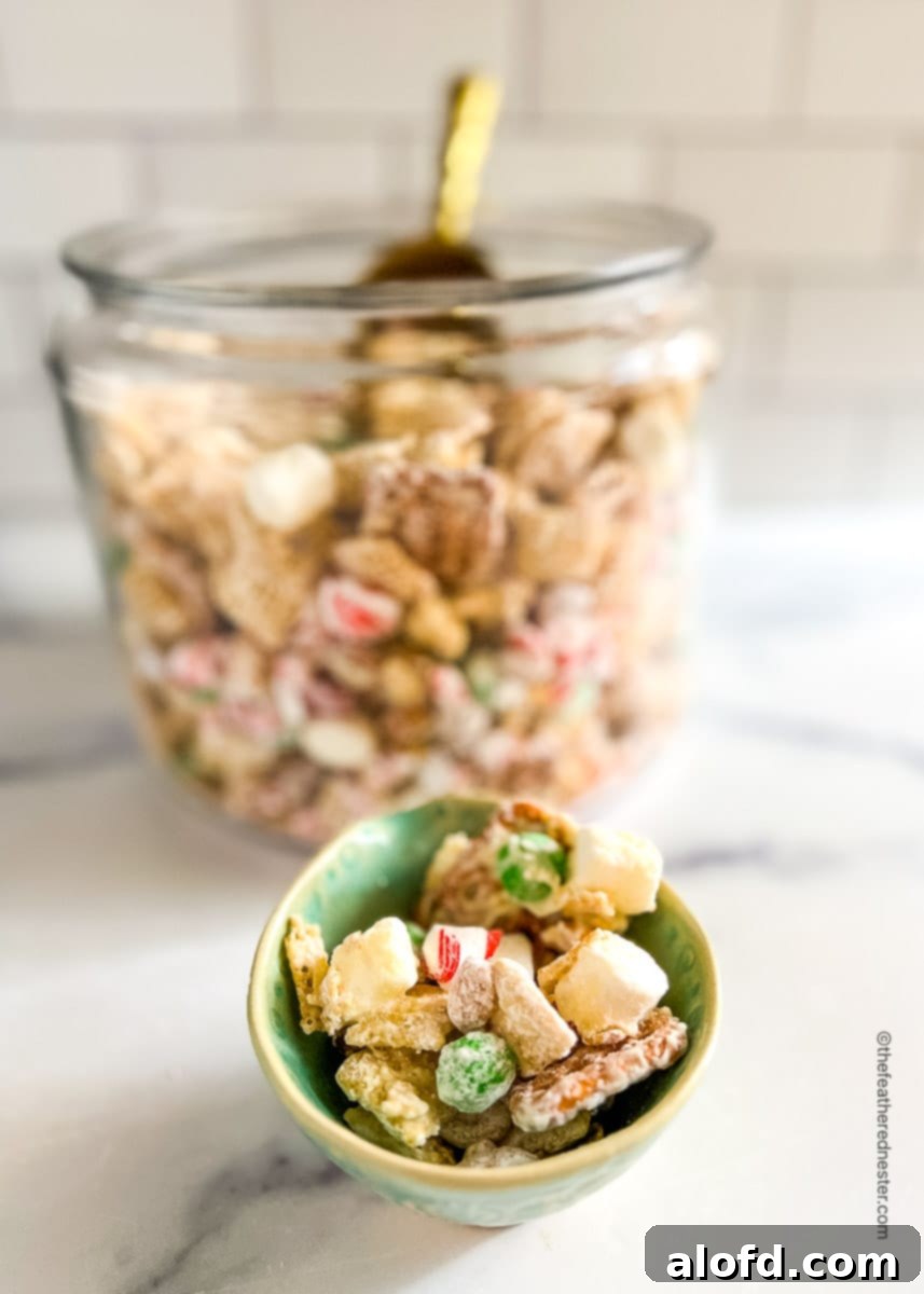 a small bowl of Christmas Chex Mix with a jar full of it in the background.