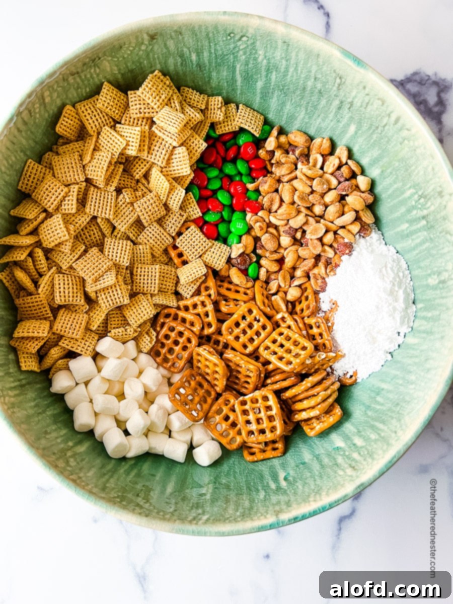 a green bowl with all the ingredients needed to make the Christmas Chex Mix recipe.