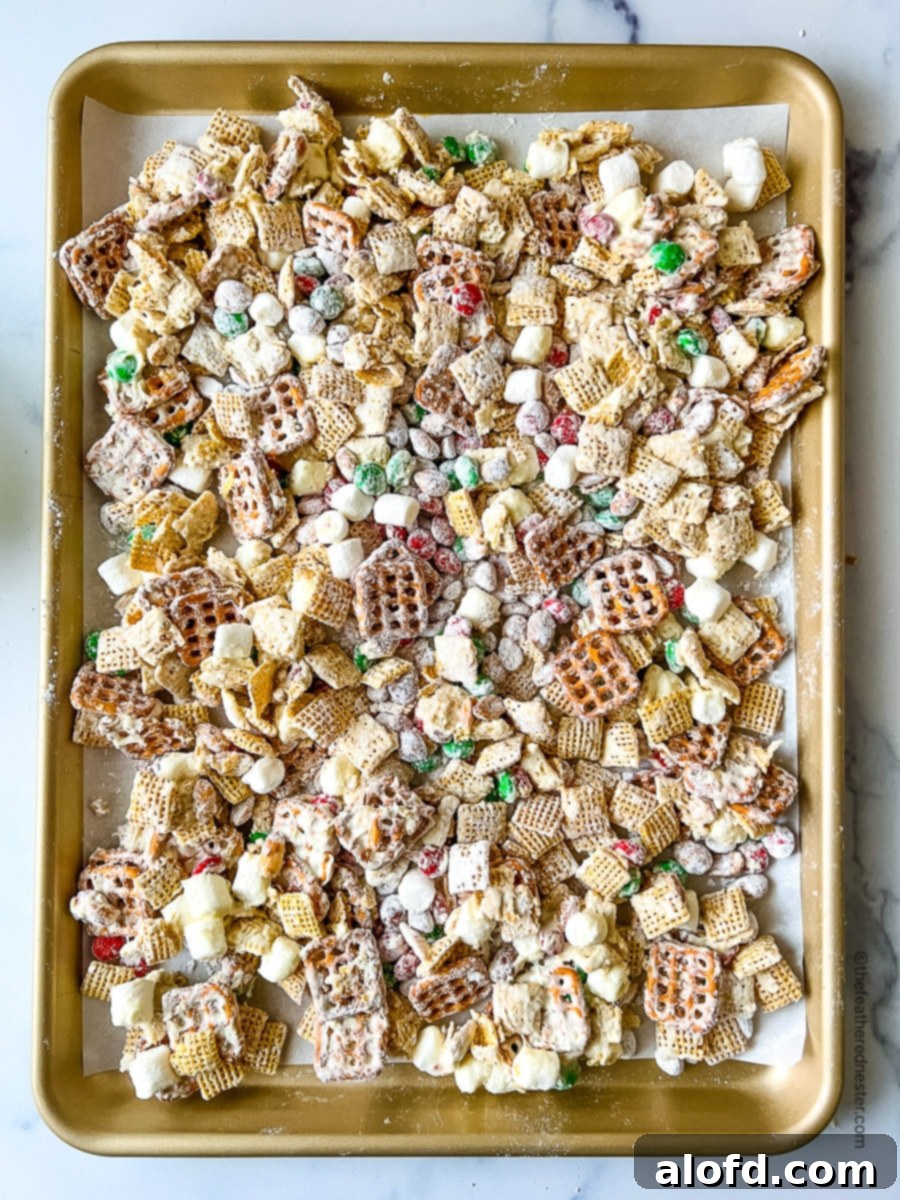 a baking sheet full of Christmas Chex Mix drizzled with white chocolate.