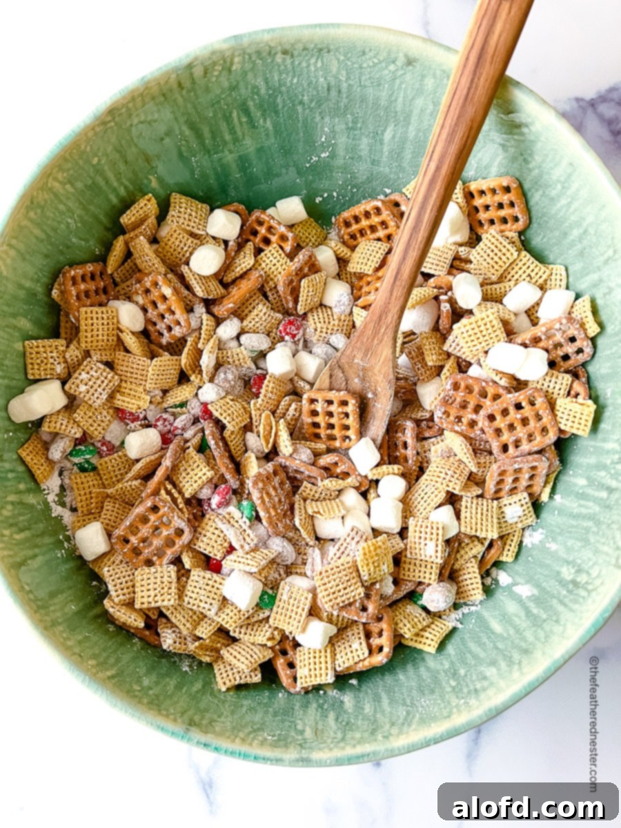 a green bowl with Christmas Chex Mix with a wooden spoon.