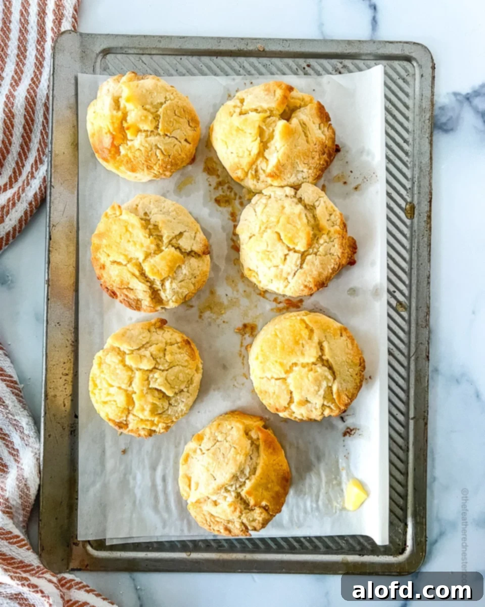 Freshly baked Bisquick rolled biscuits cooling on a parchment paper-lined baking sheet, showcasing their golden-brown tops.