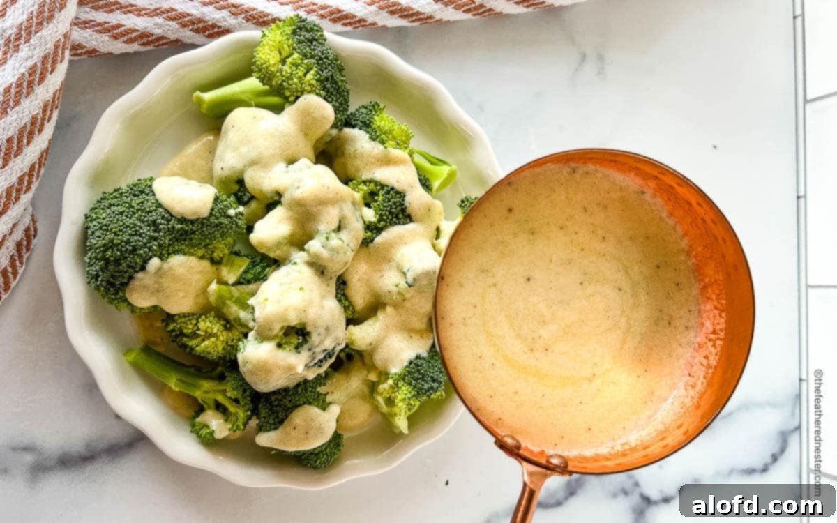 Velvety Cheese Béchamel 11 brocolli on a plate getting drizzled by white cheese sauce.