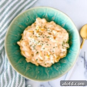 square photo of slow cooker mac and cheese on a green bowl and a spoon at the side.