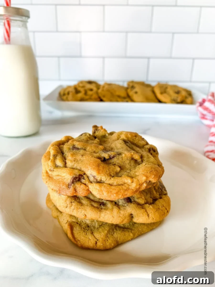 White plate topped with golden-brown chocolate chip cookies made without brown sugar, with a bottle of milk in the background.