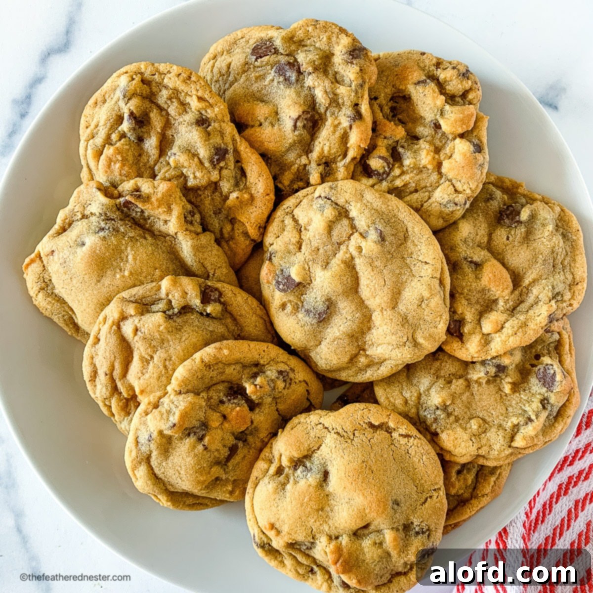 A stack of golden chocolate chip cookies, baked without brown sugar, resting on a pristine white plate.