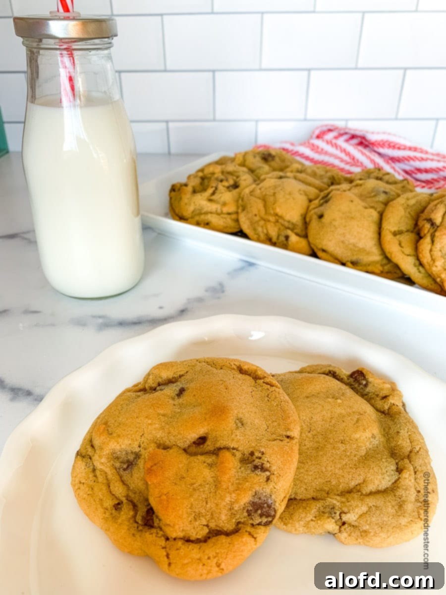 A charming scene with golden chocolate chip cookies without brown sugar on a white plate, complemented by a bottle of milk in the background, creating a cozy and inviting atmosphere.