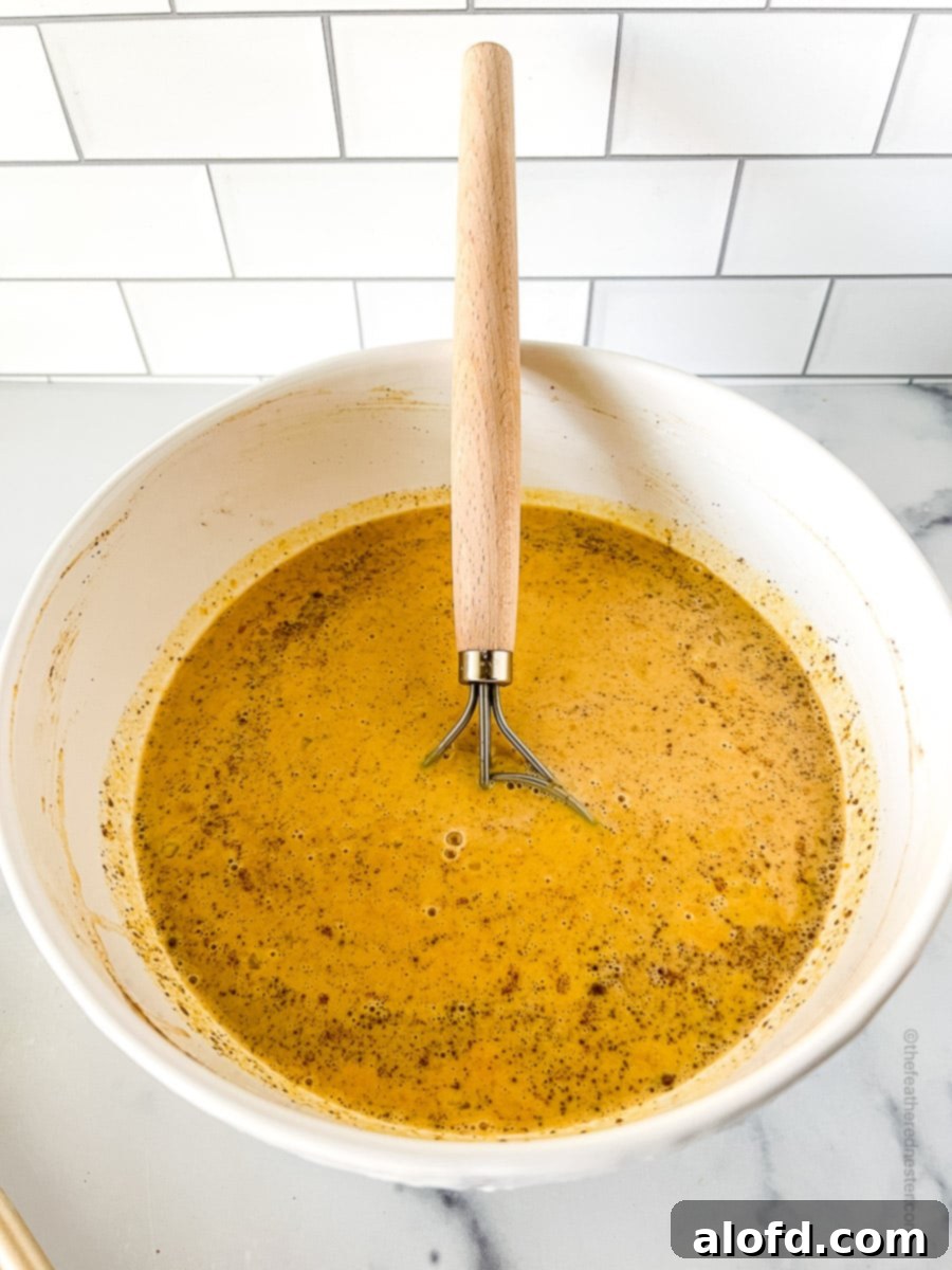 The smoothly mixed pumpkin custard filling ingredients in a large white bowl, ready to be poured.