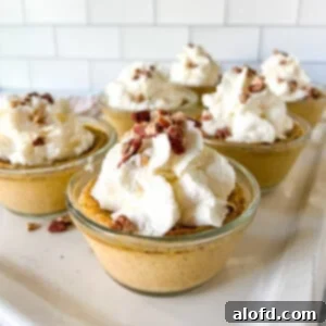 Square photo of six cups of pumpkin custard with whipped cream and nuts on top, showcasing its creamy texture.