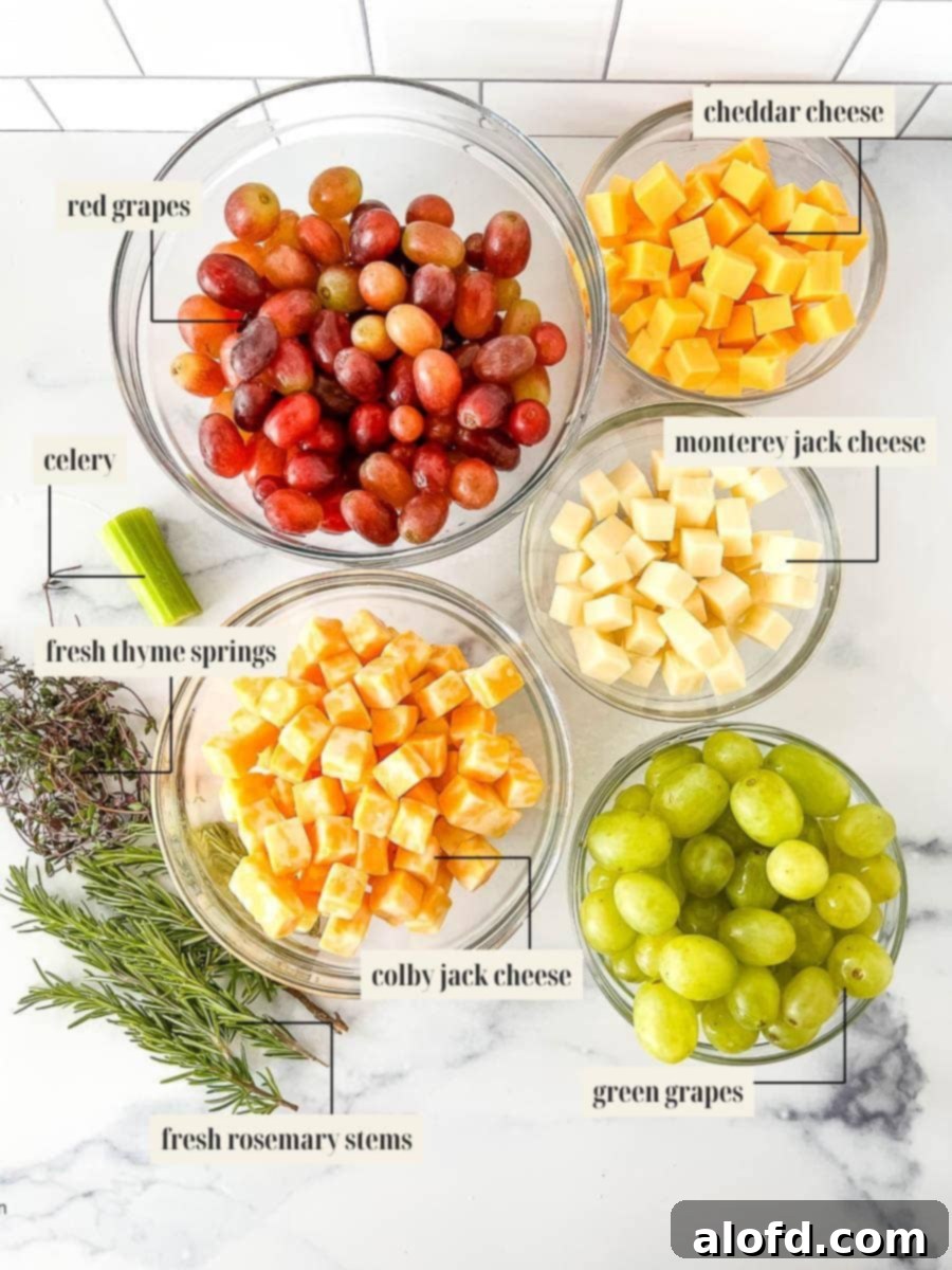 Whimsical Christmas Tree Fruit and Cheese Display 3 Ingredients needed to make the Christmas tree appetizer which consist of red grapes, green grapes, Colby jack cheese, Cheddar cheese, Monterey jack cheese, thyme springs, rosemary stems, and celery.