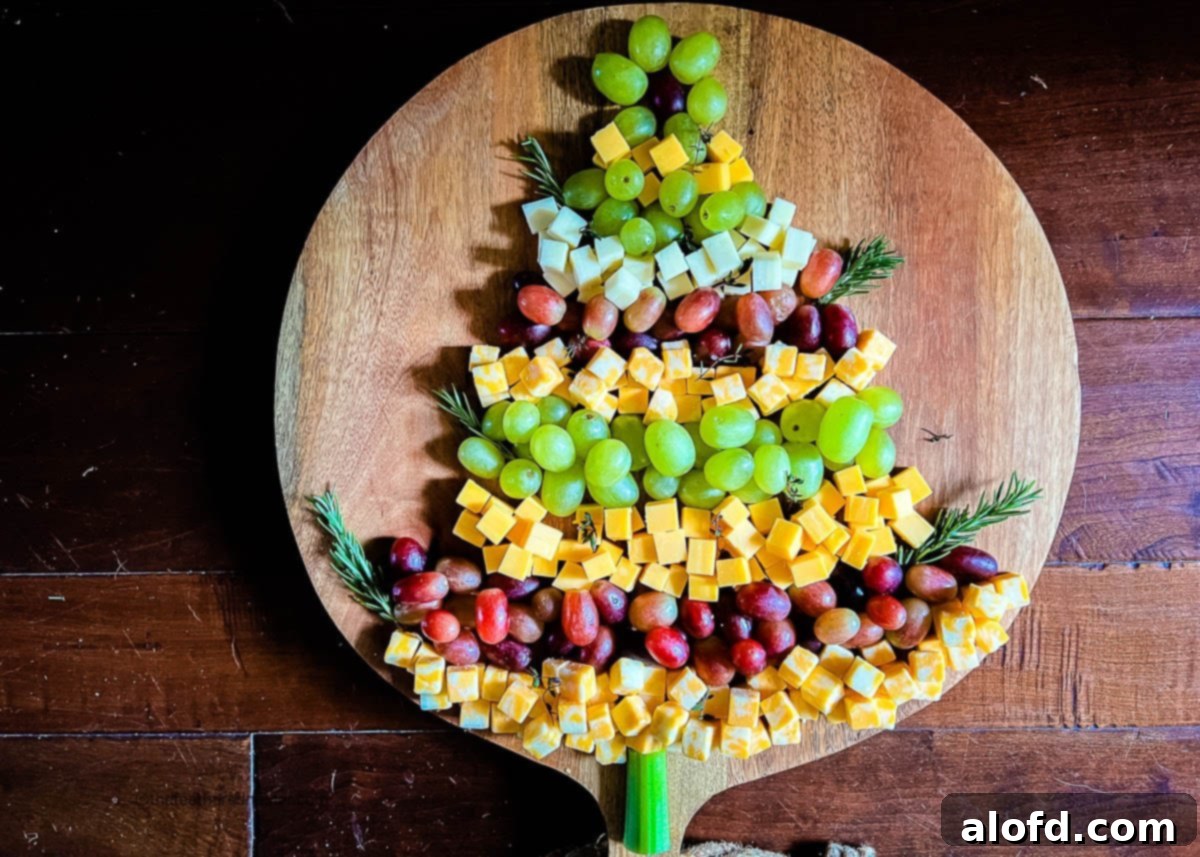 Whimsical Christmas Tree Fruit and Cheese Display 6 Horizontal photo of a Christmas Tree Cheese Appetizer on a wooden board with a dark background.