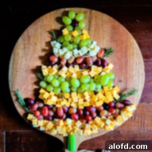 Whimsical Christmas Tree Fruit and Cheese Display 7 Christmas Tree Cheese Appetizer on a wooden board with a dark background.
