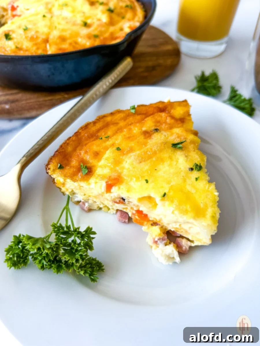 A perfectly cooked slice of ham and cheese frittata presented on a plate.
