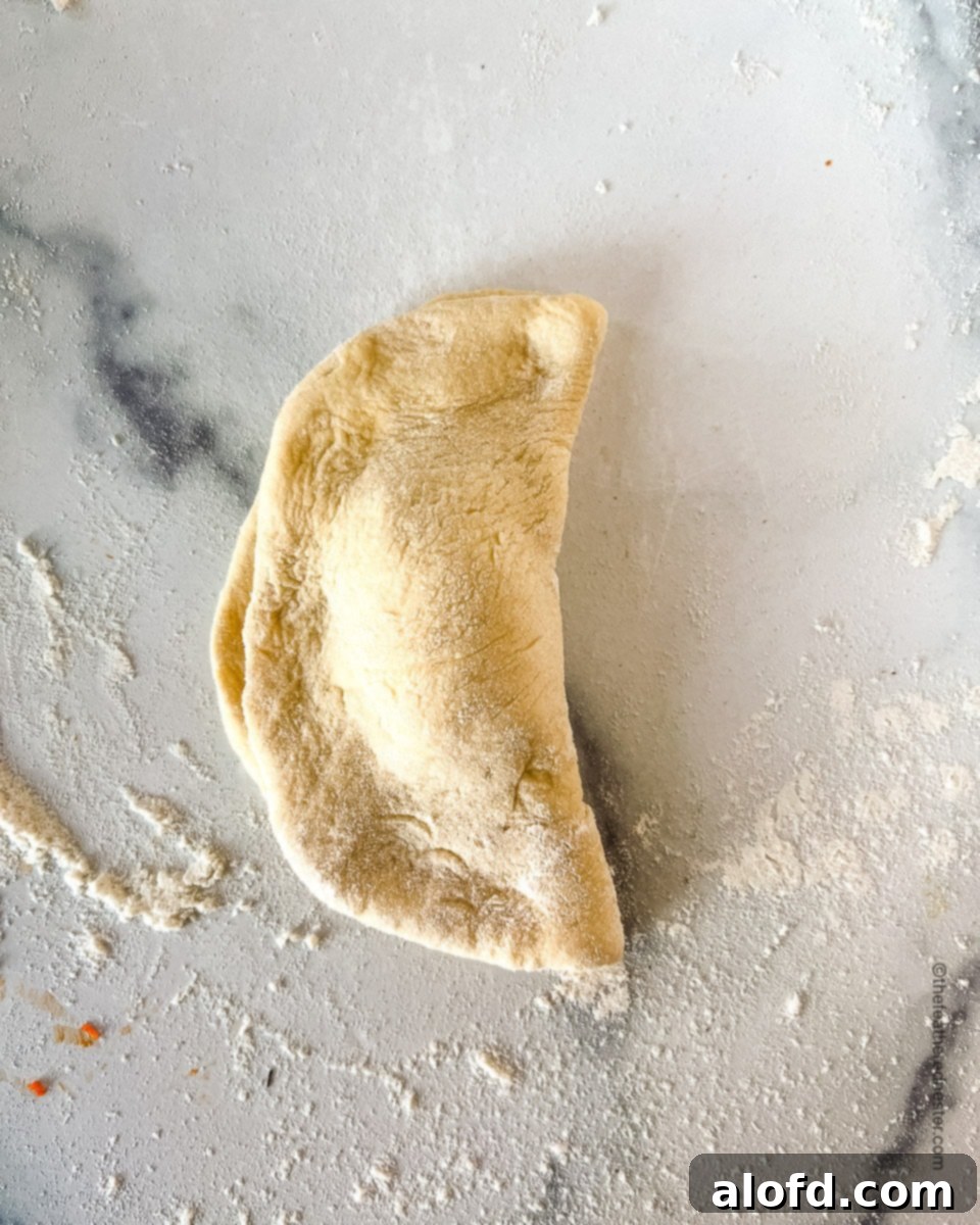 Savory Pepperoni Calzone Pockets 12 A perfectly folded and crimped unbaked calzone, ready for the oven.