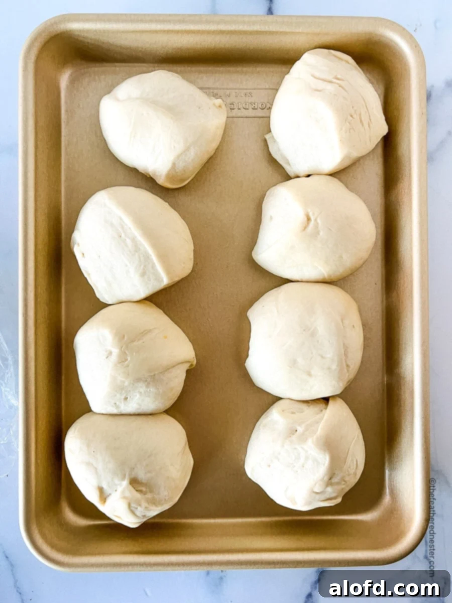 Savory Pepperoni Calzone Pockets 9 Eight thawed dough balls resting on a baking sheet, ready to be rolled out.