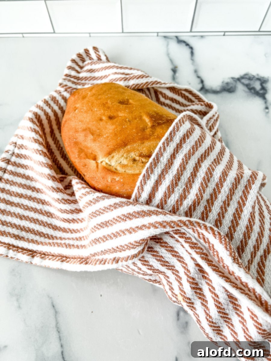 Storing sourdough bread in a brown and white striped kitchen towel.